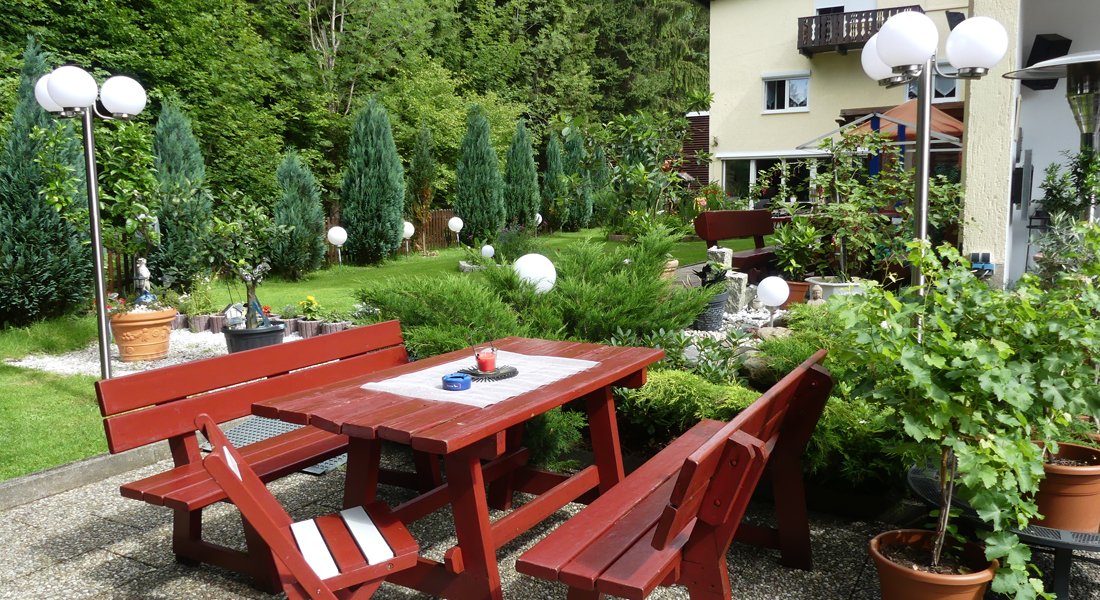Sitzplatz im Garten mit roter Holzbank