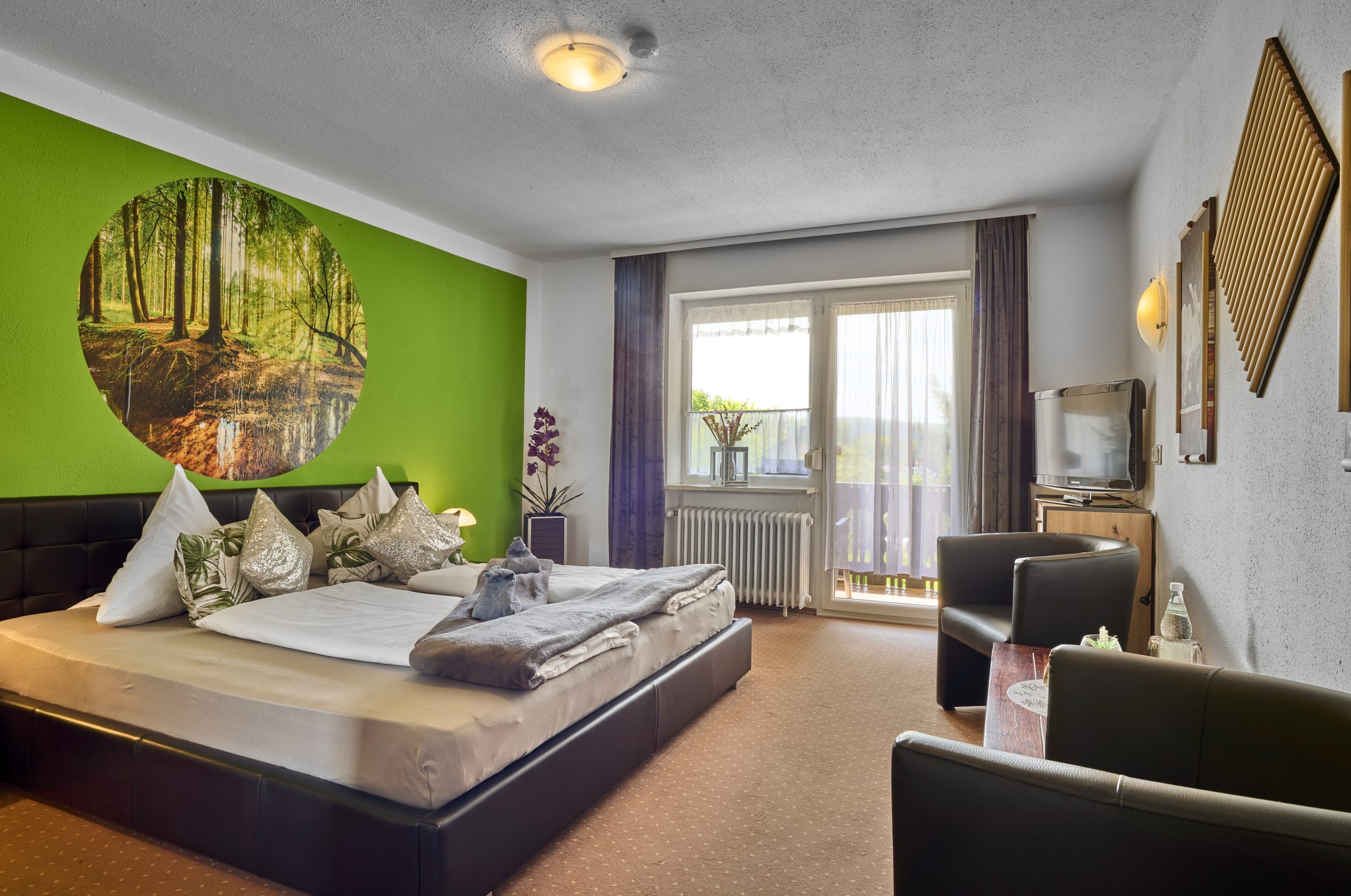 Mehrbettzimmer mit grüner Waldwand und Sitzecke